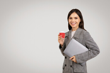 Smiling businesswoman with coffee and laptop in jacket, free space