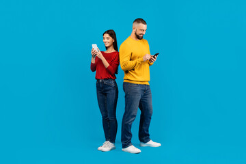 Young Man and Woman Using Smartphones Against Blue Background