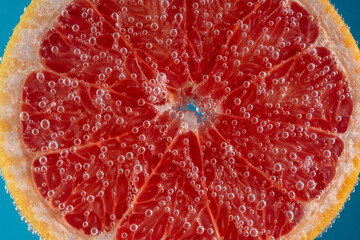 Close up view of a slice of grapefruit in soda water with bubbles. Summer drink concept.