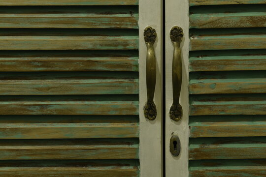 Antique style louvers with brass handles and keyhole on a wooden cupboard - interior design