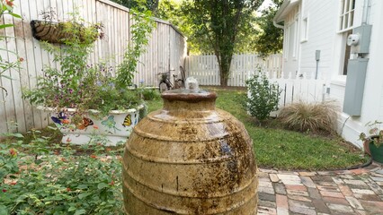 Obraz premium large old water barrel in the garden area near a fence