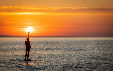 Scenic view of Neptune's statue in the sea at golden sunset