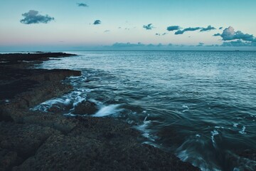 Stunning shot of a blue ocean, with waves rolling along the shoreline