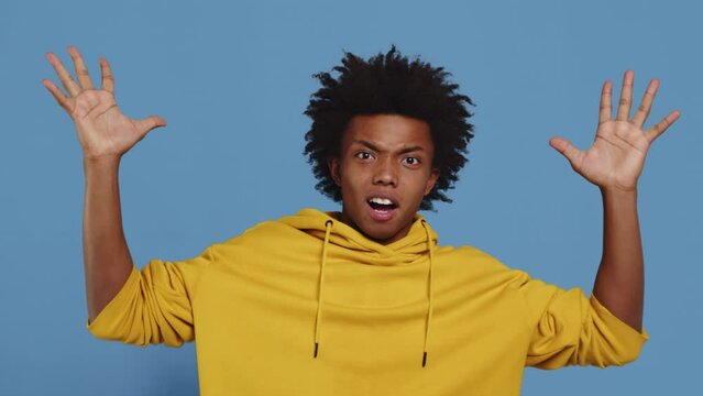 Portrait of a young black guy feeling extremely worried and shocked, touching her head and showing a mind explosion gesture on a blue background in the studio