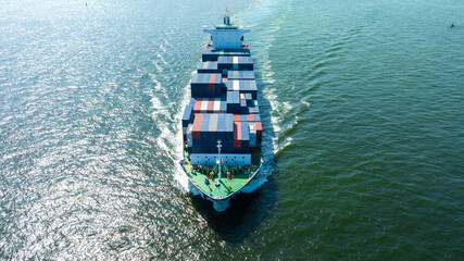 Aerial front view of cargo ship with contrail in the ocean sea ship carrying container and running...