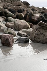 Beach with a cluster of rocks on the wet sand.