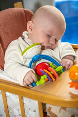 bébé endormi sur sa chaise haute avec son jouet préféré