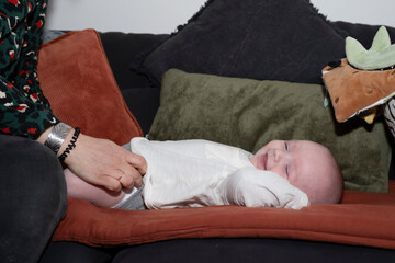 bébé sur le canapé en train de rigoler sous les chatouilles de sa mère