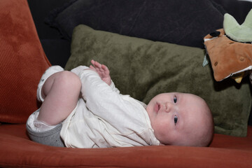 bébé sur le dos sur le canapé jouant avec ses pieds