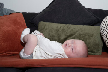Petit bébé allongé sur un canapé et riant