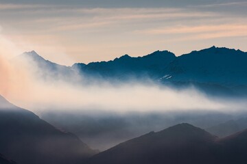 Picturesque landscape featuring a mountain range surrounded by fluffy clouds at sunset