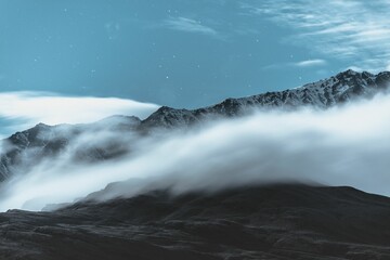 Picturesque winter landscape featuring a snow-capped mountain surrounded by fluffy clouds