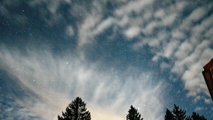 Night sky filled with an array of fluffy clouds illuminated by starlight.
