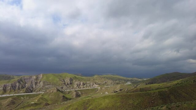 Time lapse of green landscape with hills and valleys under cloudy blue sky