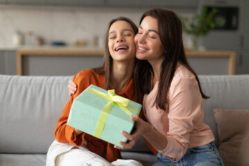 Happy mother congratulating her loving daughter with birthday at home, give her gift box and...