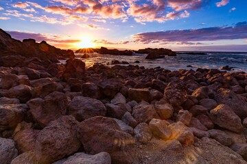 Breathtaking view of an orange and purple sunset over a rocky shoreline