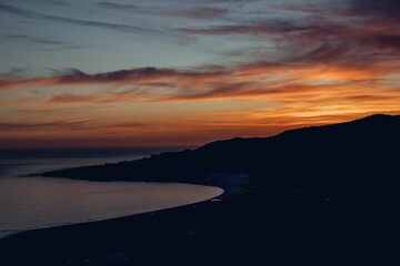 Fototapeta premium Beautiful scene of a vibrant sunset over the sandy beach and hills in Tarifa, Spain