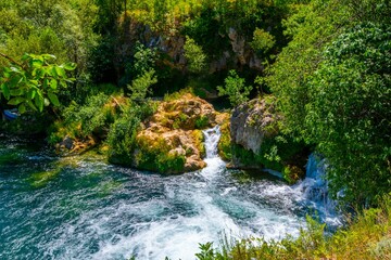 Tranquil scene of a lake surrounded by greenery near the Kravica Waterfall in Bosnia and Herzegovina