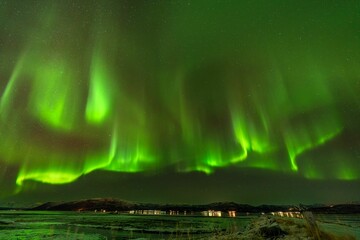 Green auroral light streaking through the sky in the middle of the night