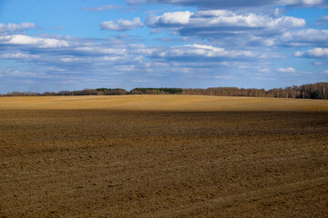 The image shows an expansive ploughed field under a cloudy sky.