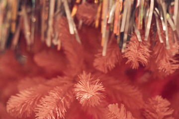 Side view of pink Christmas tree with metallic tinsel glitter rain, background with copy space. Branches with silver fringe curtains, selective focus, bokeh. Concept of textured background, wallpaper.