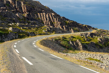 An empty winding road at the coast of Barents Sea in a rocky landscape, Finnmark Norway