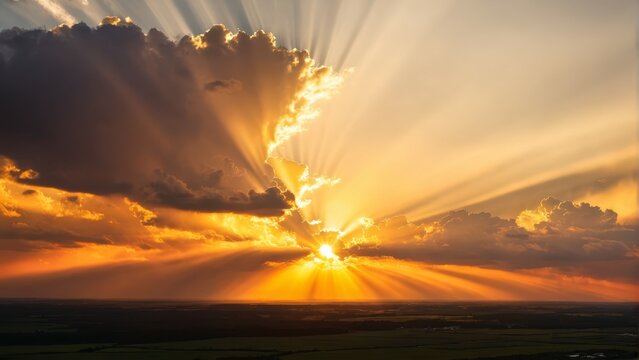   The sun's rays penetrate the clouds, illuminating the expansive green and yellow grass below