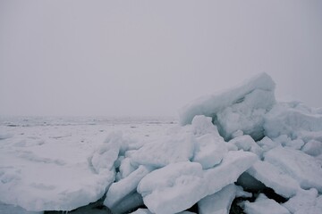 Serene winter landscape with large frozen ice blocks resting on a snowy shoreline