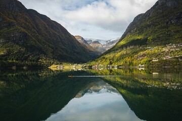 Idyllic landscape featuring a small boat rowing in front of a glacier in Norway on a tranquil lake