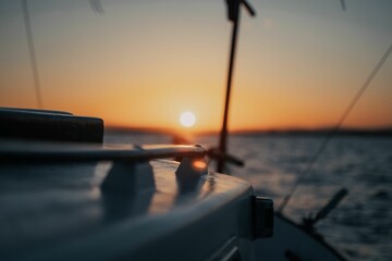 sun setting on the sea from the side of a sailboat