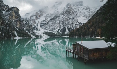 Small wooden hut situated on the edge of the tranquil Braies Lake in Dolomites, Italy.