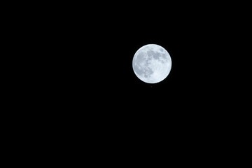 a very bright full moon shining through the sky at night