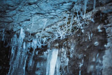 Close up shot of a rocky wall with several icicles hanging off of it