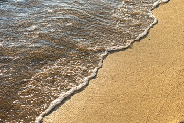 Scenic view of a tranquil beach with a wave crashing onto the shore.