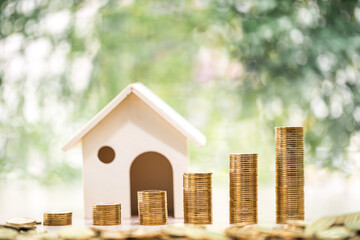 Home model and stack gold coin put on the desk in the public park, Business investment loan for...