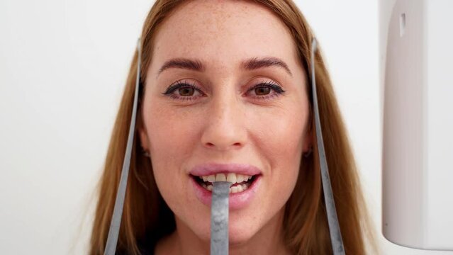 Close-up of woman's face with head positioned in cephalometric panorama x-ray machine. Female patient standing in dental x-ray machine for dental radiography. Woman making panoramic shot of jaw.