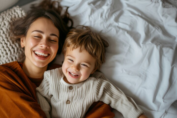 Candid Joyful mother and son sharing a laugh while lying in bed, capturing a moment of happiness and family love