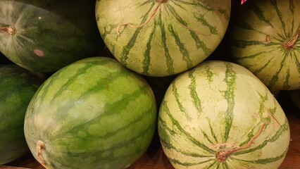 Close up pile of tasty fresh watermelons sold at the market as a background.