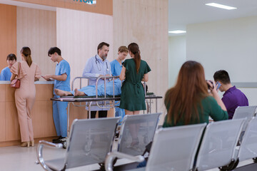 Doctors and nurses are waiting to transfer a patient lying on a bed for treatment, with relatives closely watching over him.