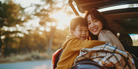 Asian Mother and Son Embracing in Car Trunk, Warm Sunset Hues Enhancing Tender Family Moment
