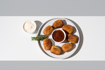 Plato de croquetas de aperitivo sobre una mesa blanca y fondo gris