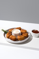 Plato de croquetas de aperitivo sobre una mesa blanca y fondo gris