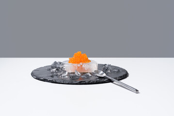 Caviar de salmón sobre hielo en un plato de pizarra. Comida gourmet sobre fondo gris	