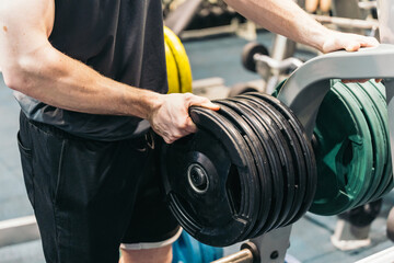 Side View of Anonymous Athlete Adjusting Weight Plate in Gym. Anonymous athlete in gym, adjusting weight plate on machine.