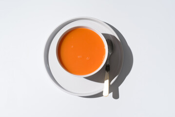 Sopa de zanahoria en un plato sobre fondo gris y blanco. Vista superior - obrazy, fototapety, plakaty