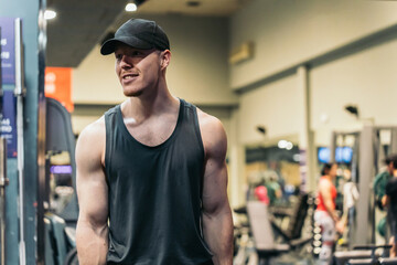 Muscular redhead gym athlete in cap, smiling, looking sideways.