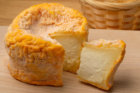 Langres cheese refined with champagne and a piece on a cutting board close up