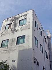 Old building with many glass windows, showing signs of weathering.
