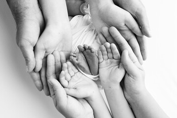 The palms of the father, the mother are holding the foot of the newborn baby. Feet of the newborn on the palms of the parents. Studio macro black and white photo of a child's toes, heels and feet. - obrazy, fototapety, plakaty