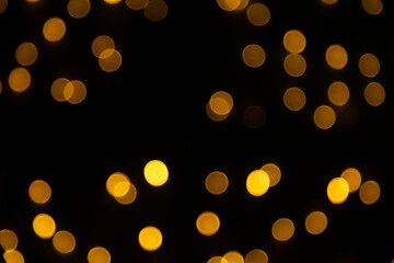 Fundo preto com luzes amarelas desfocadas em bokeh.
